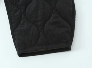 Detail shot of wavy quilted pattern on black jacket with contrast lining and piping