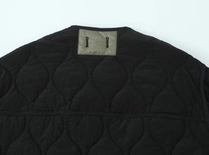 Detail of onion-quilted jacket liner with olive green patch and functional buttonholes