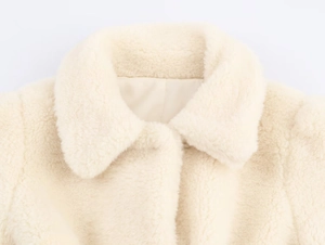 Detail of faux shearling texture and lapel collar on the creamy white winter jacket