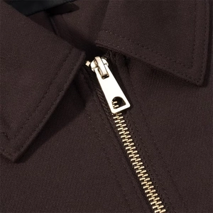 Detailed macro view of high-quality golden metal zipper on a dark brown jacket collar