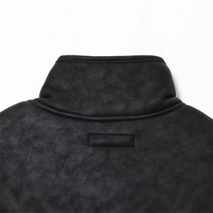 Gros plan du col montant en cuir noir d'une veste avec boucle de suspension et coutures fines