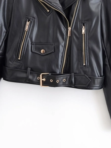 Gros plan sur une veste de motard en PU noir avec fermetures éclair et boucles dorées