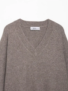 Detailed view of soft V-neck knit sweater featuring refined texture and branded neck label