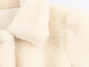 Close-up of fluffy cream faux fur fabric texture and collar detail on the jacket