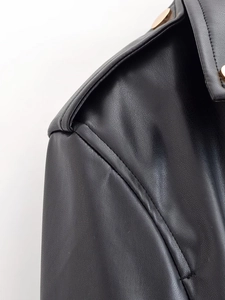 Détail de l'épaule d'une veste en similicuir noir avec bouton doré et coutures fines