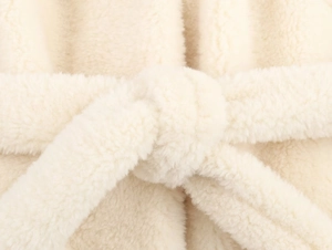 Macro shot of faux fur texture and waist tie on the cream winter coat jacket