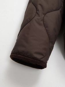 Macro view of brown quilted jacket sleeve with corduroy trim edge and detailed stitching