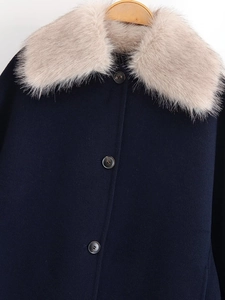 Close-up of navy wool coat featuring premium faux fur collar and dark button closure