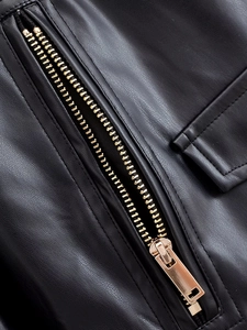 Gros plan sur la texture cuir noir et la fermeture éclair dorée de la veste
