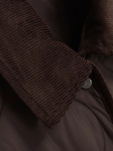 Macro detail of dark brown corduroy collar and quilted fabric with metal snap button