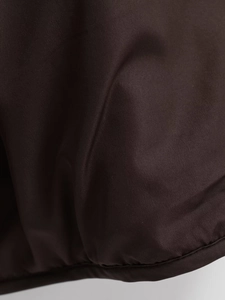 Detail of dark brown padded jacket fabric featuring a corduroy collar and neat hem stitching