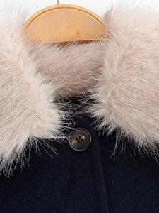 Close-up of faux fur collar and dark brown button on navy blue wool jacket
