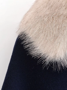 Detail of dark blue wool fabric and plush beige faux fur collar on women's winter jacket