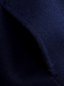 Macro shot of side pocket stitching and thick navy blue wool fabric on women's winter jacket