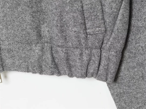 Detail of gray wool jacket featuring elastic hem construction and precision stitching