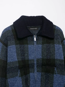 Close-up of vintage plaid knit cardigan with dark blue ribbed collar and metal zipper detail
