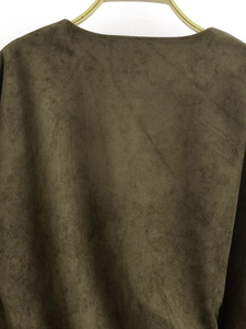 Detailed close-up of army green faux suede top fabric texture on a golden hanger