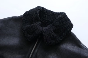 Detail der schwarzen Lammfelljacke mit Kunstpelzkragen und silbernem Reißverschluss