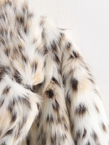 Close-up of leopard print faux fur texture with long fluffy fibers in cream and brown