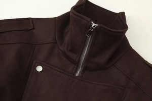 Close-up of brown suede jacket detailing silver metal zipper and stitching texture