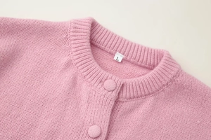 Detailed macro view of pink mohair knit cardigan featuring fabric-covered buttons and crew neck