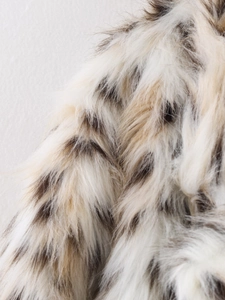 Close-up of premium leopard print faux fur texture with long fluffy white and brown fibers