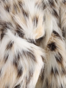 Detailed close-up of fluffy faux fur fabric with beige base and brown leopard spots