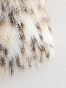 Detailed close-up of fluffy faux fur fabric with realistic snow leopard print pattern