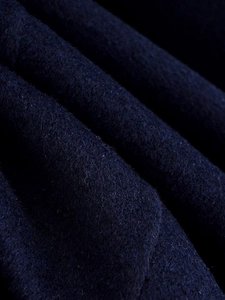 Macro detail of navy blue wool fabric showing dense fiber texture and premium material