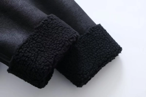 Detailaufnahme des Ärmels einer schwarzen Lammfelljacke mit Kunstlederstruktur und Fleecefutter