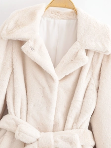 Detailed close-up of cream faux fur jacket texture with lapel collar and matching belt