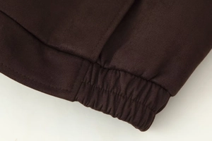 Close-up of brown suede jacket hem showing elastic waist and precise double stitching
