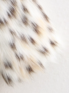 Macro shot of fluffy cream faux fur texture with dark brown tips for winter coats