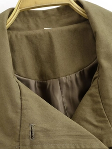 Detail of army green trench coat showing twill fabric texture and smooth satin lining