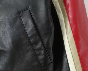 Detailed macro view of black lychee texture PU leather jacket with red white stitching