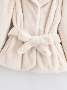 Detailed macro view of cream faux fur texture and waist belt tie on the coat