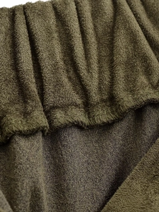 Detailopname van olijfgroene suède stof met de textuur van een elastische tailleband