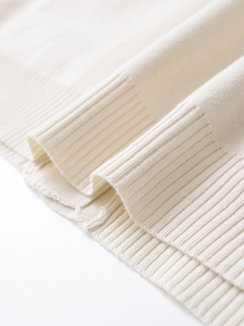 Detail of soft white ribbed knit hem and fine texture on a stylish V-neck cardigan