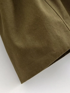 Detail of olive green trench coat showing high-density twill fabric texture and weave