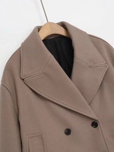 Detailed view of camel wool coat with large lapel, double-breasted black buttons, and lining
