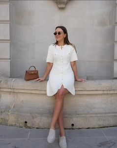 Detail of white short sleeve knit dress showing button closure and textured fabric