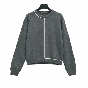 Close-up detail of dark grey knit sweater with white asymmetric lines and ribbed neckline
