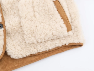 Close-up of cream faux shearling texture with brown suede trim and button detail