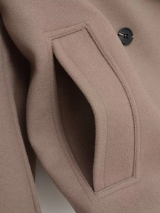 Detailed view of the taupe wool coat with stitching on the pocket and black button