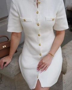 Detail of white rib-knit dress with lion-head metal buttons and decorative pockets