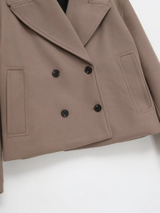 Detail of camel wool coat featuring classic double-breasted buttons and wide lapels