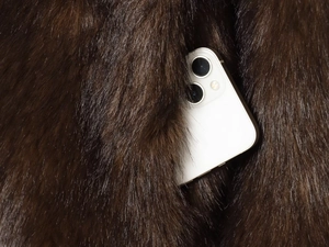 Detailed close-up of the deep brown faux fur jacket pocket with a smartphone inside