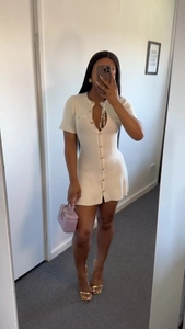 Detail of white ribbed knit mini dress featuring a button-down front and V-neckline