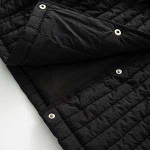 Détail de la veste matelassée noire avec coutures carrées et boutons-pression en métal
