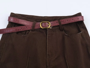 Dettaglio dei pantaloni in twill di cotone marrone scuro con cintura bordeaux coccodrillo